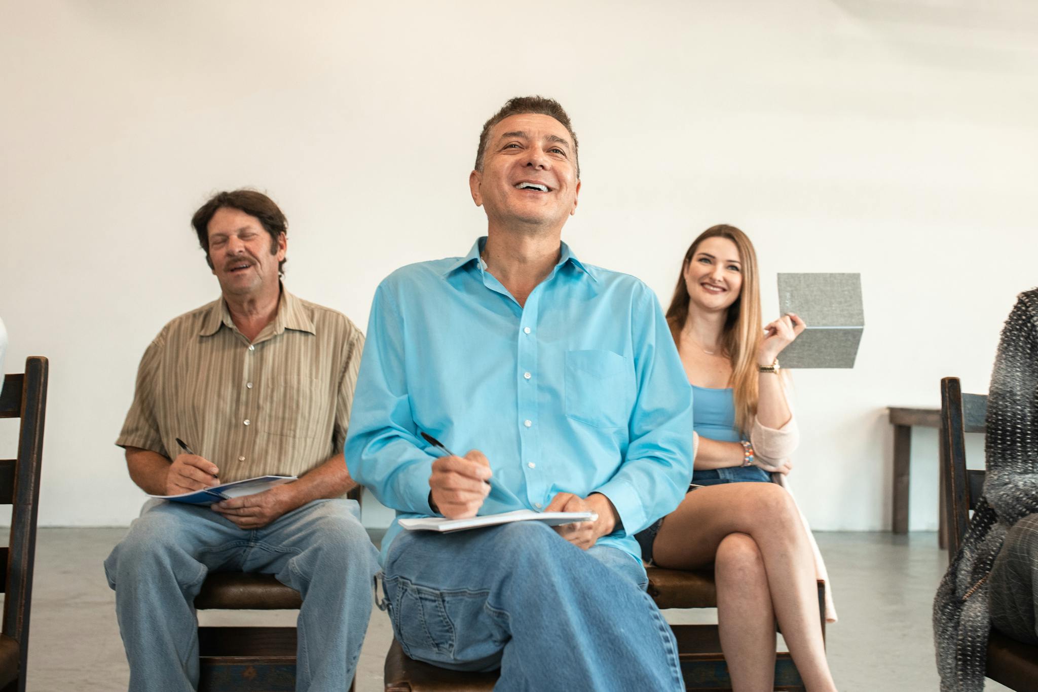 A group of adults smiling and writing during an engaging classroom session.
