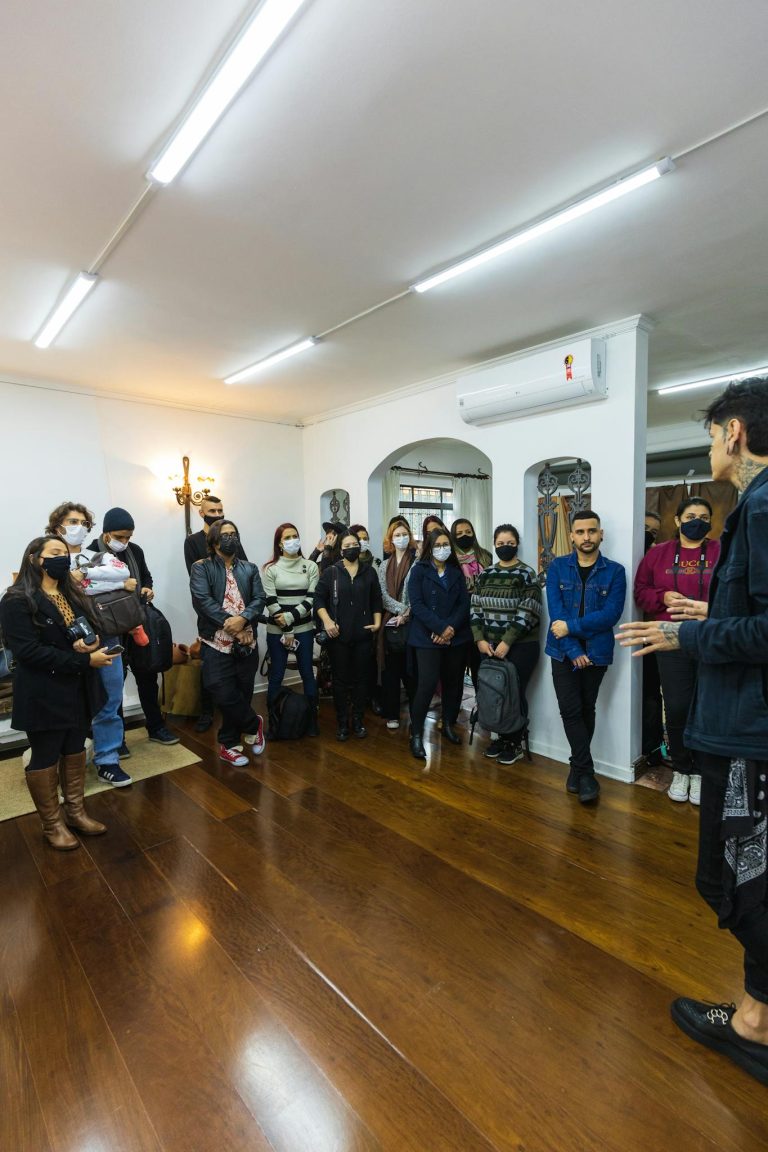 Diverse group of adults gathering indoors for a meeting, discussing topics in a well-lit room.