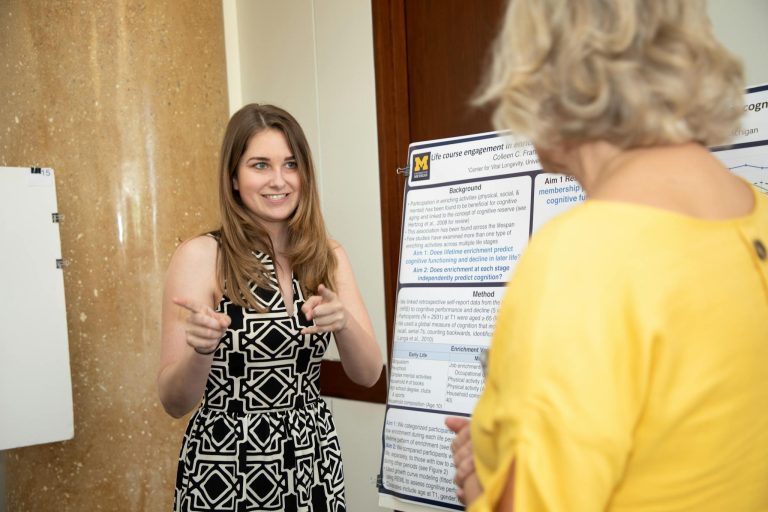 Young woman presenting research at an academic conference to a fellow attendee.